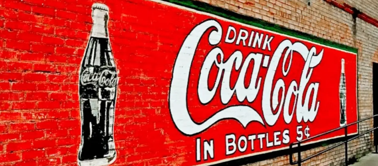 Large-scale vintage Coca-Cola mural painted on a brick exterior wall